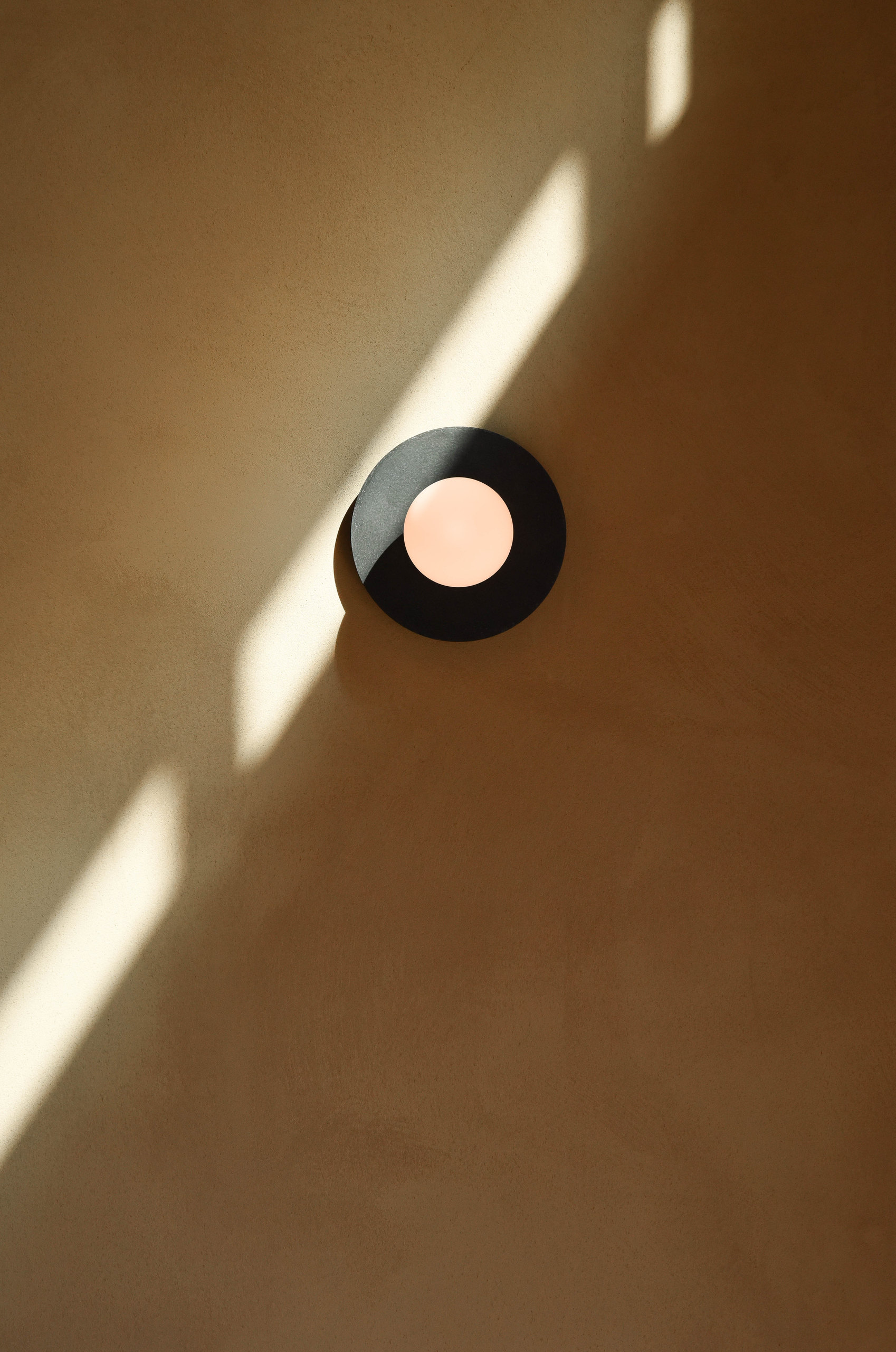 Round wall light crossed by sunlight